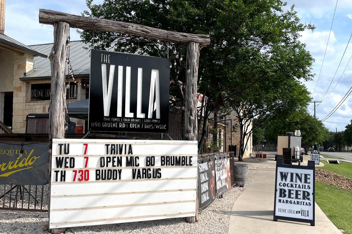 Street Sign outside The Villa that shows live music events on a board below the Bar Sign